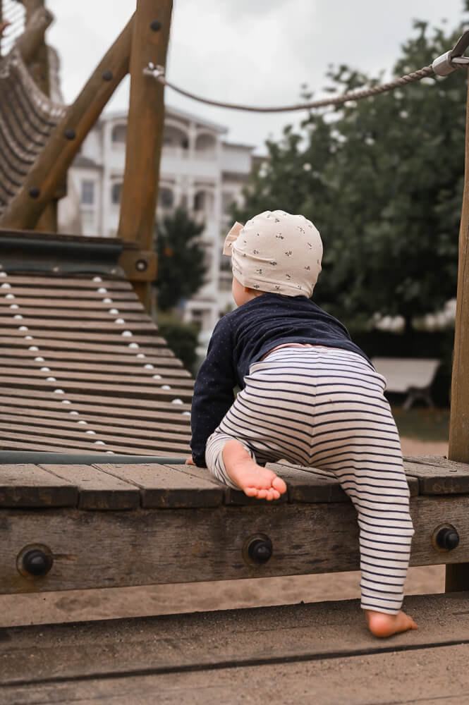Ein Kleinkind klettert auf einem Spielplatz bei einem Familienshooting in Rostock
