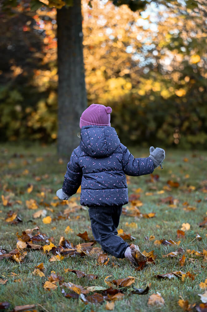 Ein kleines Mädchen läuft durch den Herbstwald bei einem Familienshooting in Rostock - Familienfotografie
