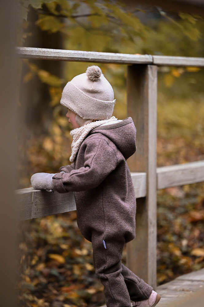 Ein Kleinkind steht auf einer Holzbrücke im Wald bei einem Familienfotoshooting in Rostock