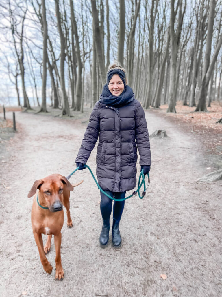 Eine Frau spaziert mit ihrem Hund im Gespensterwald bei einem Familienshooting in Rostock