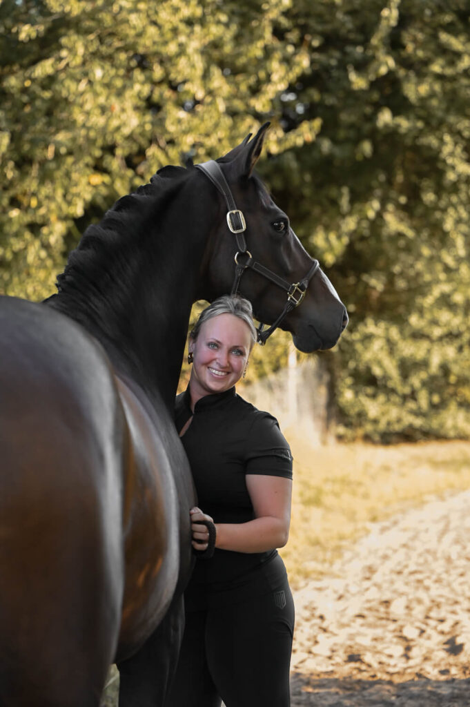 Eine hübsche Frau schmiegt sich an ihre große, schöne Stute bei einem Tiershooting in Rostock