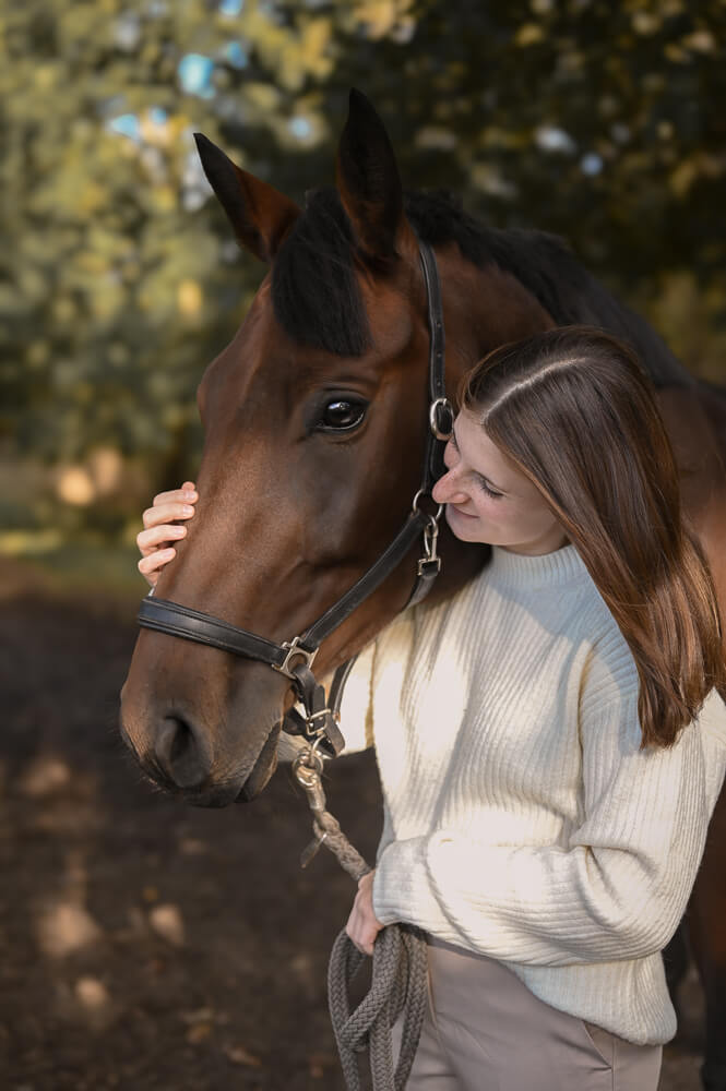 Eine junge Frau kuschelt mit ihrer hübschen Stute bei einem Pferdeshooting in Rostock