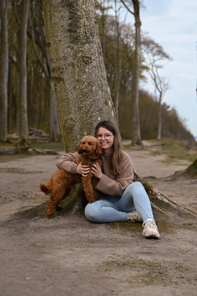 Hund und Frauchen sitzen an einem Baum bei einem Hundeshooting in Rostock